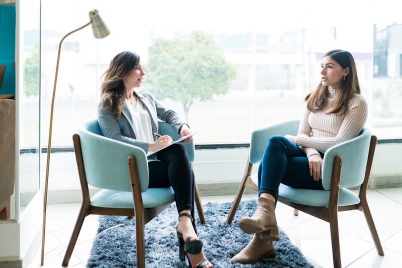 Two women sitting talking. One is a psychologist and one is a client.