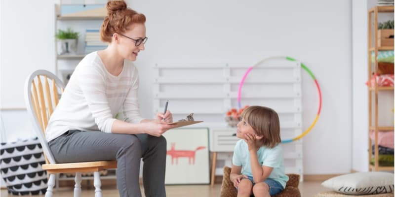 Young female psychologist helping a primary school aged boy in a session.