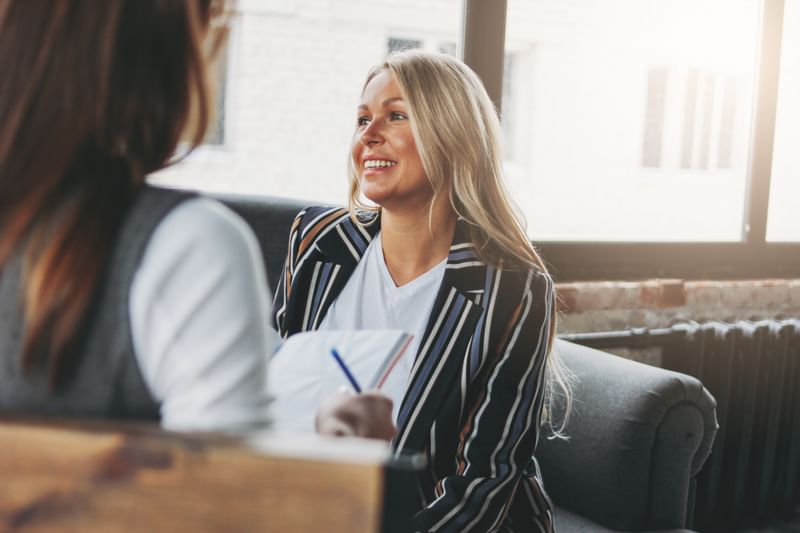 A social psychologist smiling and talking to a colleague.