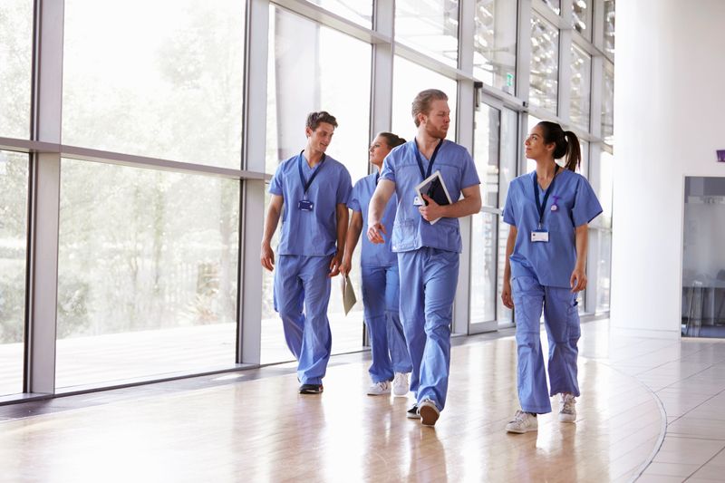 A group of nurses walk down a hospital hallway talking.