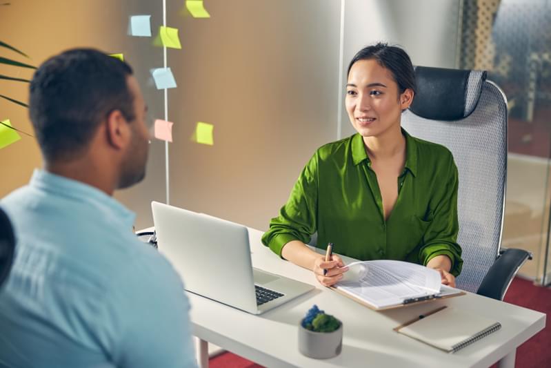 A business leader at their desk talking with a colleague. 