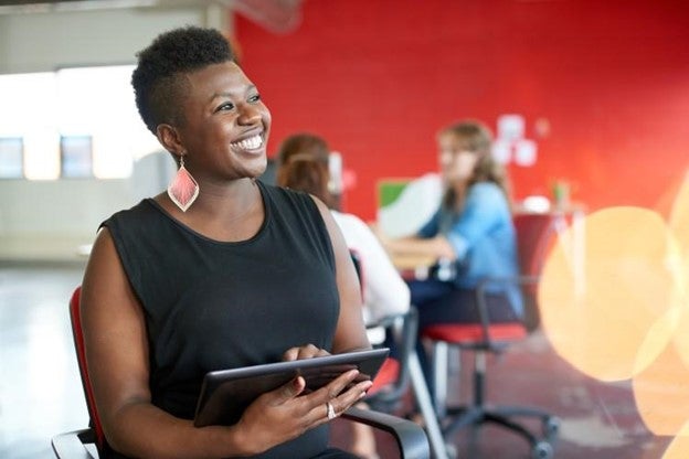 A smiling business owner uses a tablet.