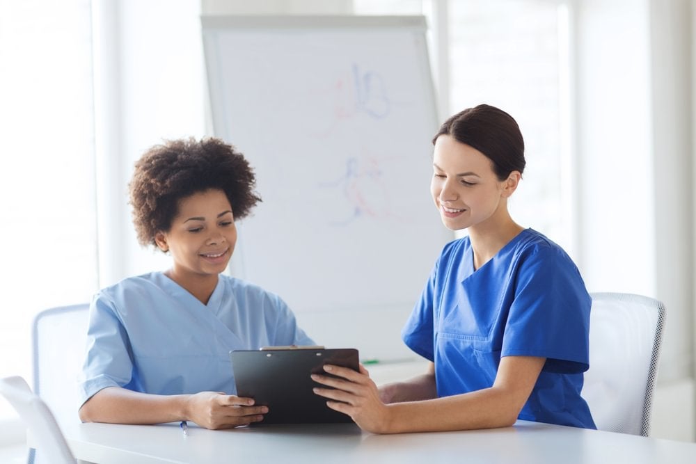 Two nurses sitting together as they inspect a document