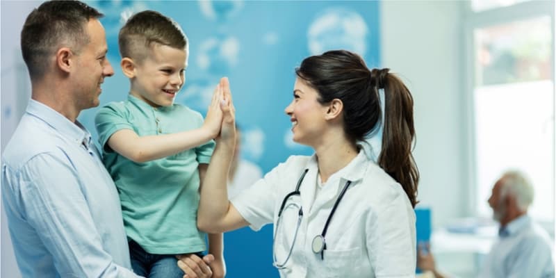 Female nurse high fiving her young patient