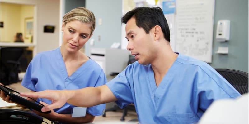 Male and female nurse wokring together using a tablet