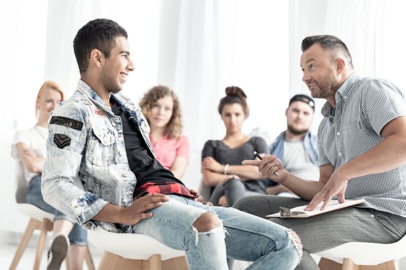 Social psychologist with a group of people discussing their behaviours