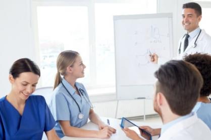 Group of happy nurses with mentor meeting and drawing on flip board at hospital