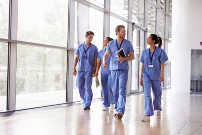 A group of nurses walk down a hospital hallway talking.