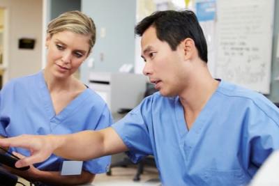 Male and female nurse wokring together using a tablet