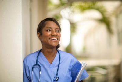 A smiling nurse wearing scrubs and a stethoscope. 